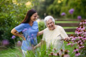 Home care nurse spending time with elderly lady patient in garden.
